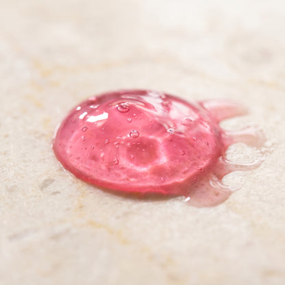 Pink water-jelly serum texture on glass