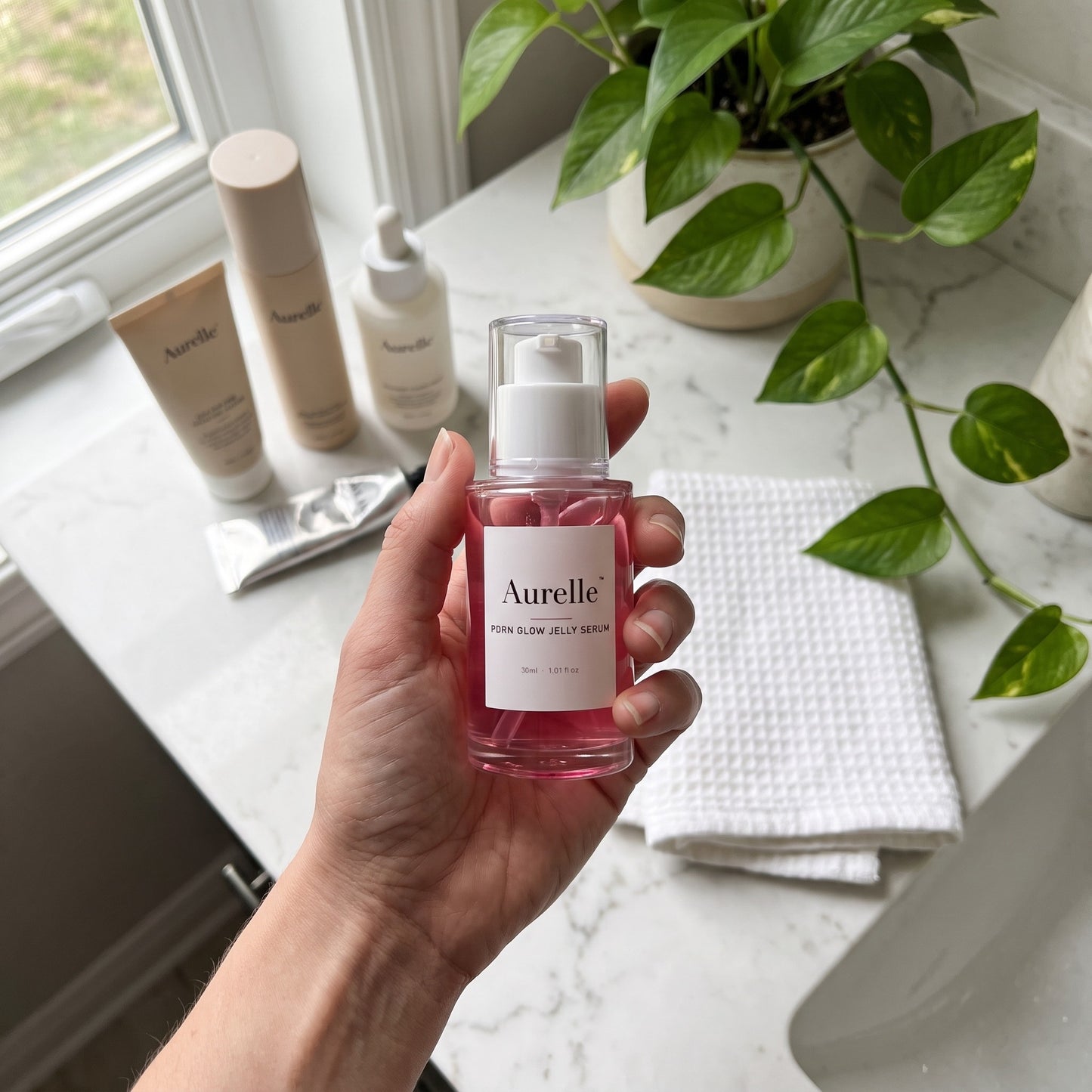 Aurelle jelly serum held over a marble bathroom counter, morning routine