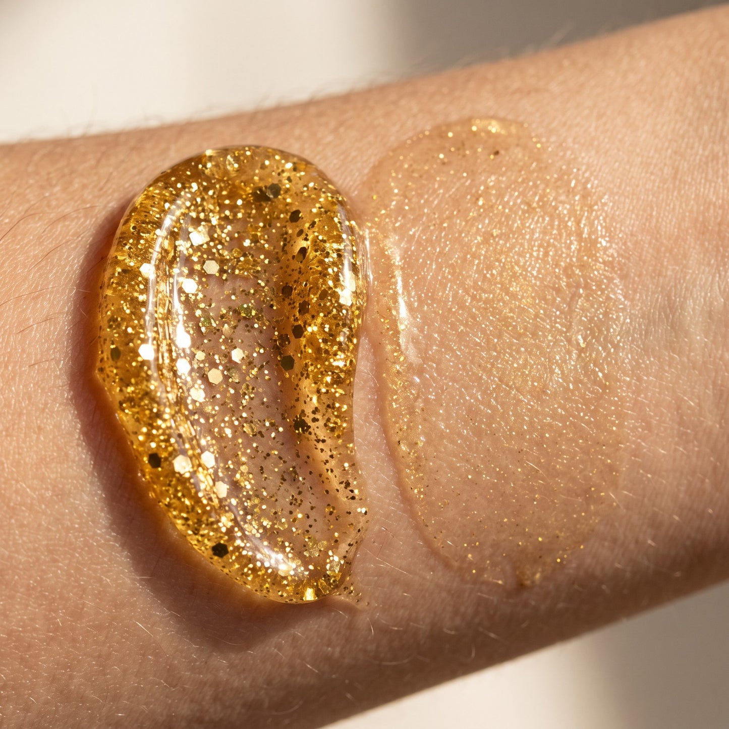 Close-up of the thick gold glitter gel texture on skin, beside an area where it has been massaged in to a golden sheen