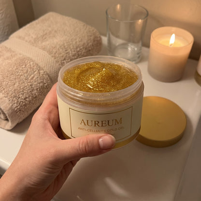 A hand holding the open AUREUM tub on a bathroom counter in evening lamplight