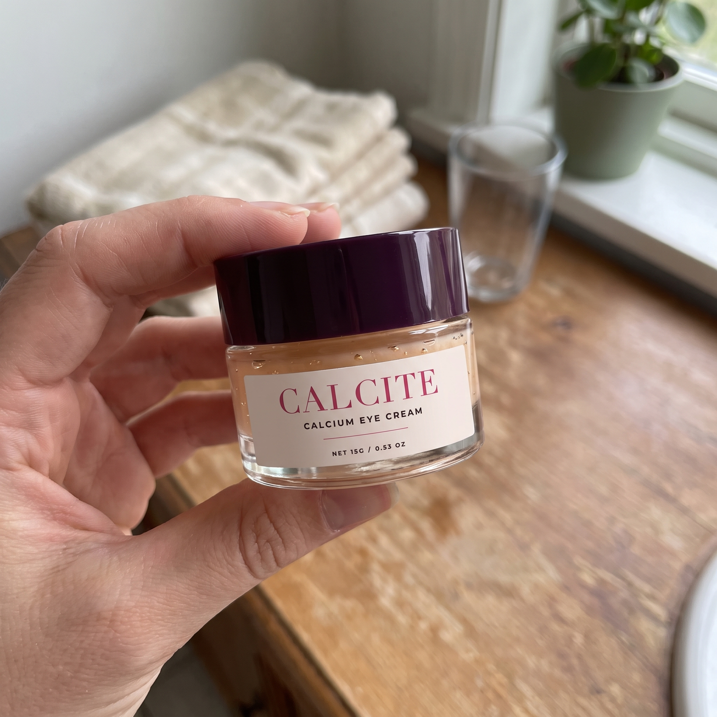Holding CALCITE calcium eye cream on a bathroom counter
