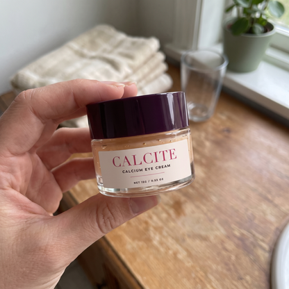 Holding CALCITE calcium eye cream on a bathroom counter